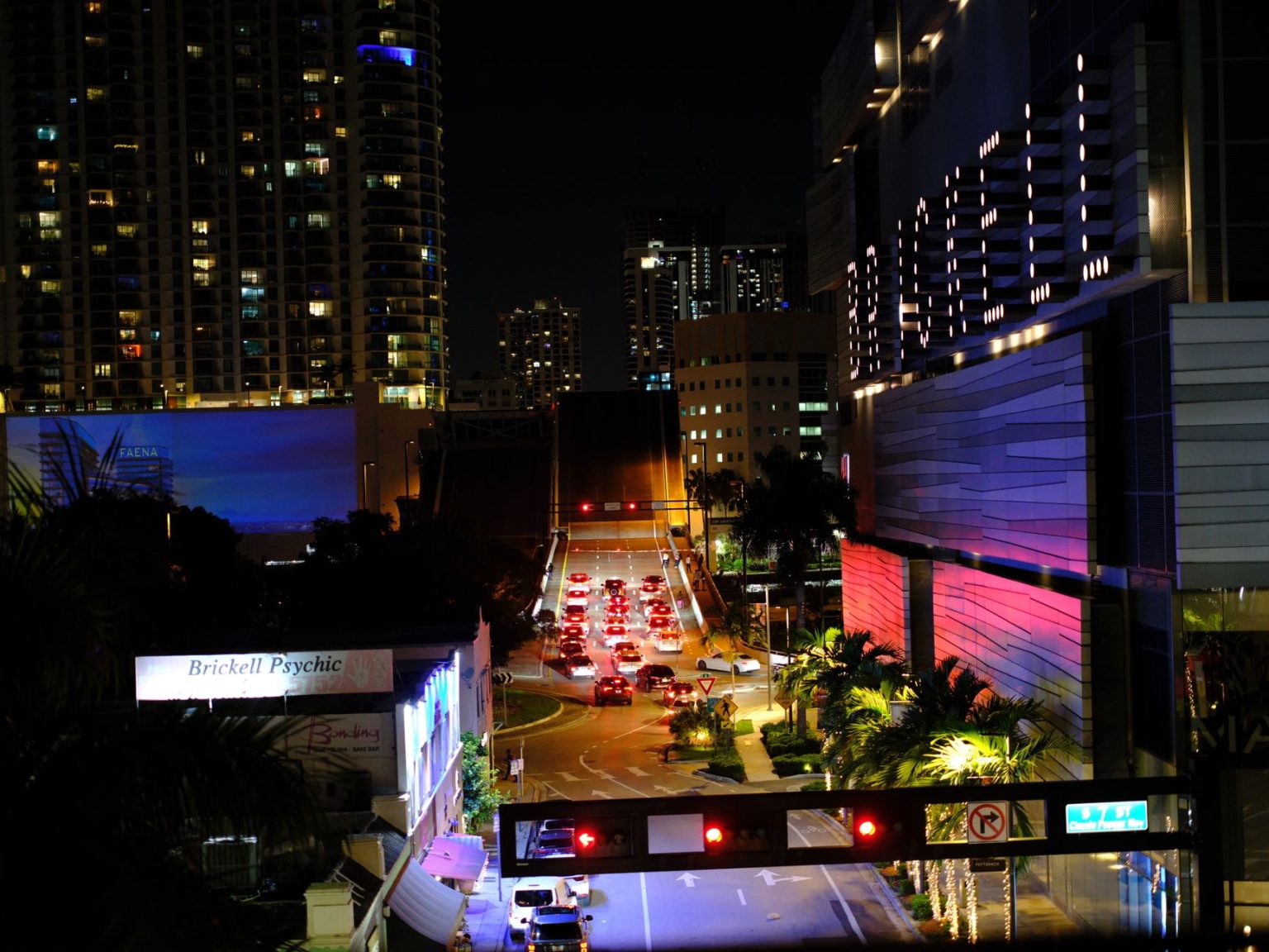 Vista noturna de Brickell, em Miami, com arranha-céus iluminados, trânsito e luzes da cidade.