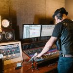 Produtor musical trabalha em uma mesa de mixagem em um estúdio profissional de gravação.