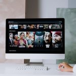 Tela de computador exibindo séries da Netflix em um espaço de trabalho moderno