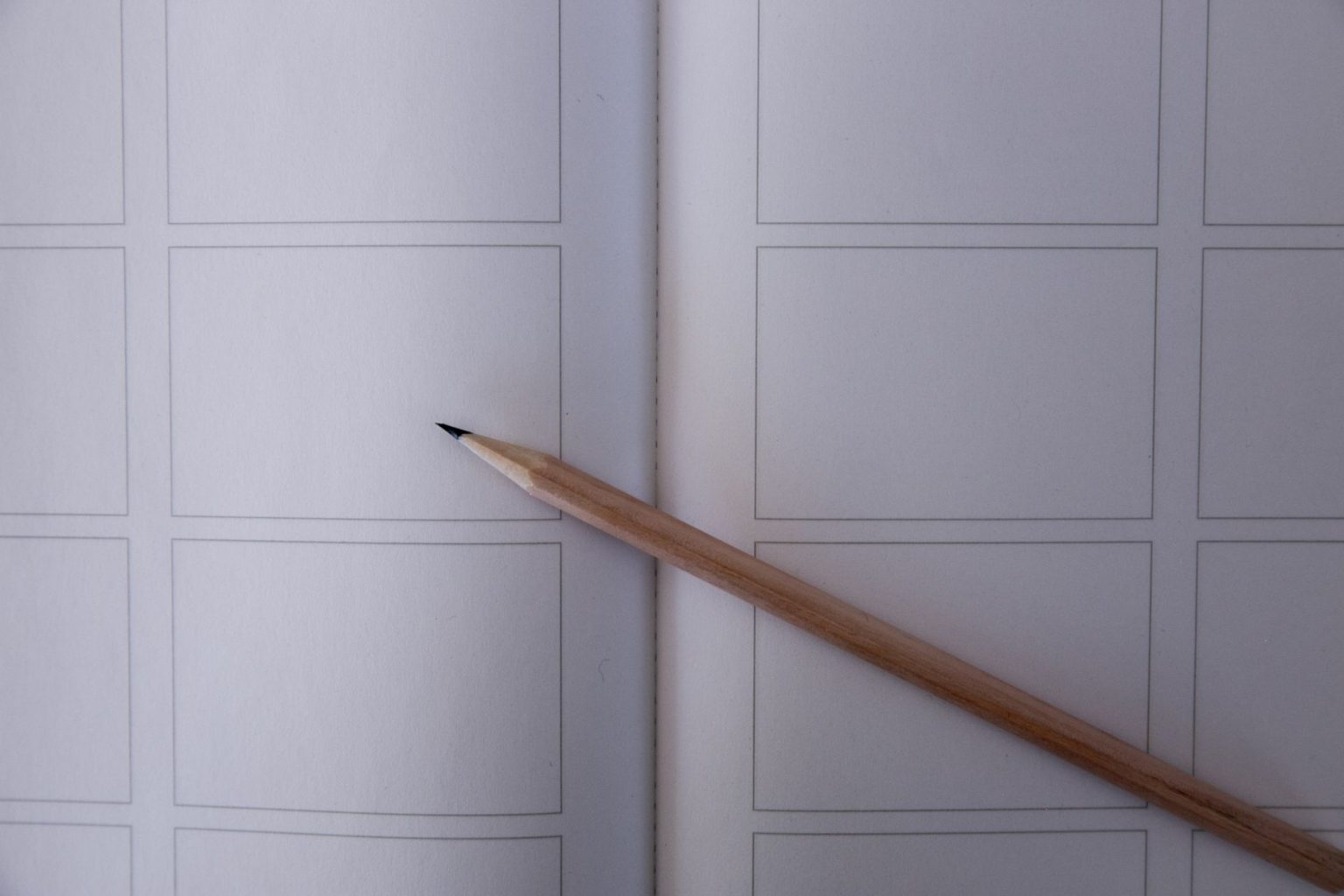Close de um lápis sobre um storyboard com quadros em branco, representando o planejamento visual de uma animação.