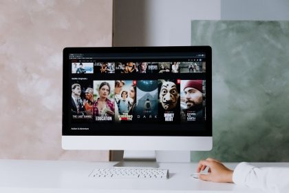 Tela de computador exibindo séries da Netflix em um espaço de trabalho moderno