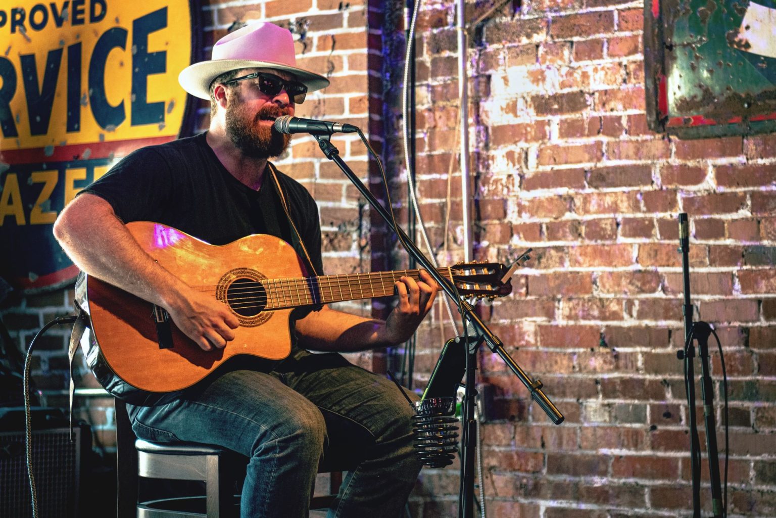 Músico toca violão em um bar de Nashville, diante de um microfone.