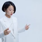 Mulher interage com uma tela transparente de aparência futurista em um ambiente tecnológico.