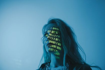 Mulher com luzes em formato de código binário projetadas sobre o rosto, em uma composição que remete à tecnologia e à segurança digital.